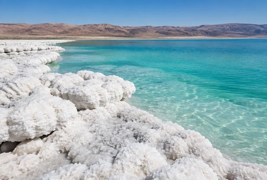White salt crust on the shore of a very salty lake with calm turquoise water